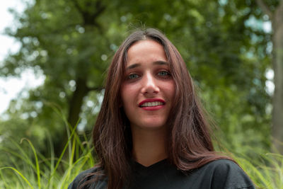 Portrait of young woman against trees