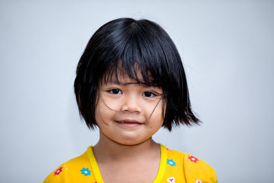 Portrait of cute smiling boy against gray background