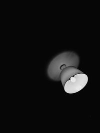 Low angle view of illuminated lamp against black background