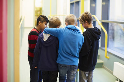 Multi-ethnic boys standing in school corridor