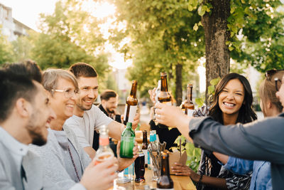 Male and female friends laughing while toasting with drinks at social gathering