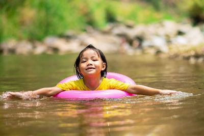 Portrait of girl with inflatable ring swimming in river