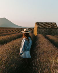 Rear view of woman standing on field against sky