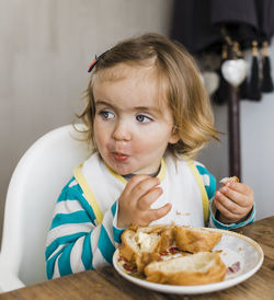 Cute girl looking away while eating food at home