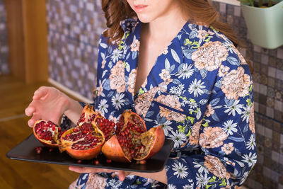 Midsection of woman holding pomegranate