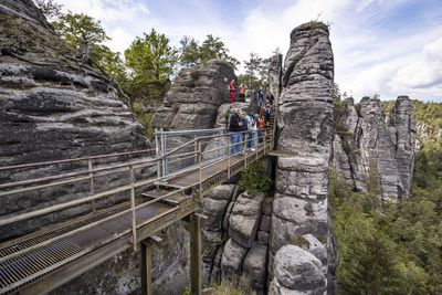 Footbridge over rocks against sky