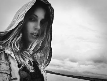 Portrait of young woman standing against sky