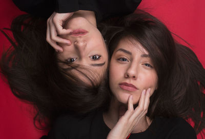 Portrait of young women lying over red background