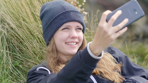 Portrait of smiling young woman holding smart phone outdoors