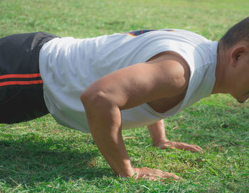 Midsection of man exercising on grassy field