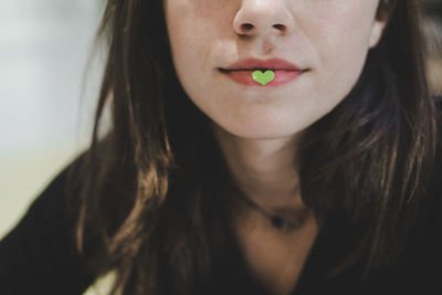 Midsection of woman with heart shape on lips