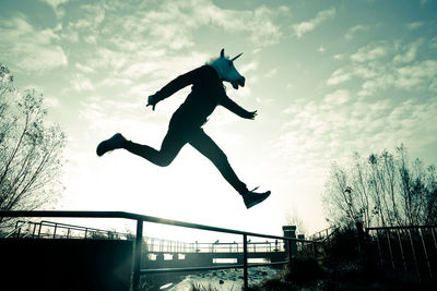 Low angle view of silhouette man jumping against sky