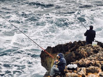 High angle view of people fishing in sea on rocks