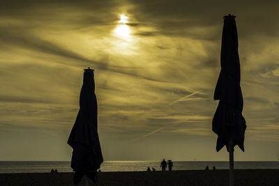 Silhouette people at beach against sky during sunset