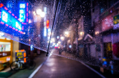 Cropped image of wet umbrella during rainy season on street at night