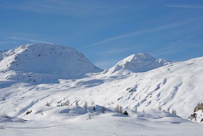 Scenic view of snow covered mountains against blue sky
