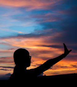 Silhouette person against orange sky during sunset