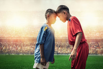 Side view of two boys standing on soccer field