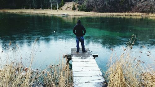 Man standing on pier at lake