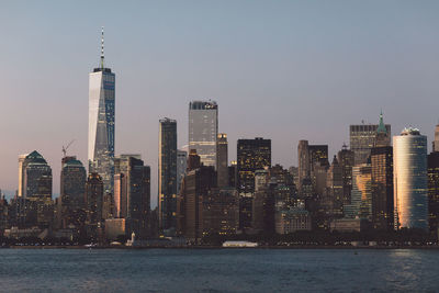 Sea by cityscape against clear sky