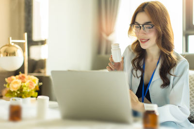 Young woman using phone while sitting on table