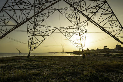 Low angle view of electricity pylon at sunset