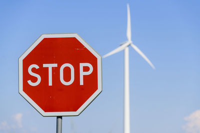 Stop sign and wind turbine on background