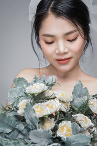 Close-up of woman holding flower bouquet against white background