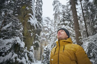 Man standing in forest against trees during winter