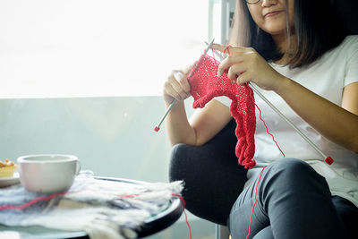 Midsection of woman knitting while sitting at home