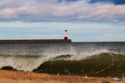 Lighthouse by sea against sky