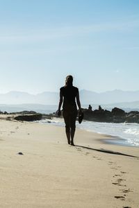 Rear view of woman standing at beach