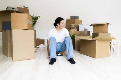 Full length of young woman sitting on wooden floor
