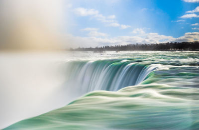 Scenic view of waterfall against sky during winter