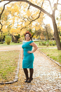 Full length portrait of woman standing by tree