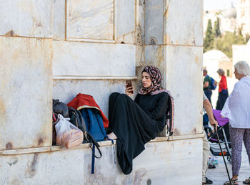 Panoramic view of people sitting on wall