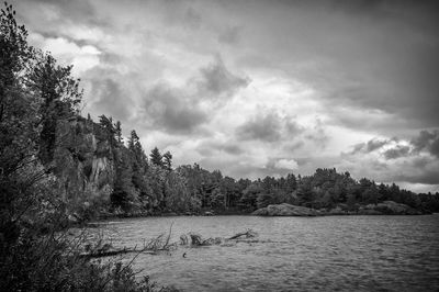 View of calm river against cloudy sky