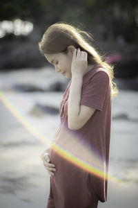 Portrait of young woman looking away while standing outdoors