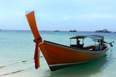Longtail boat in sea against sky