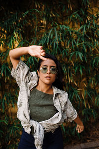 Latina girl with green sunglasses dancing surrounded by green leaves