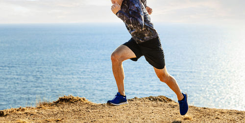 Male athlete start running on sea background