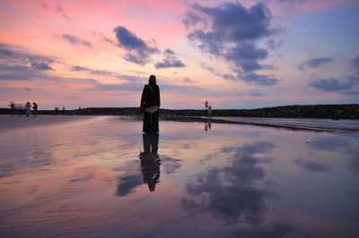 Man standing on beach against sky during sunset