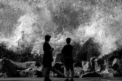 Rear view of people looking at waterfall