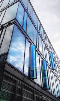 Low angle view of glass building against sky