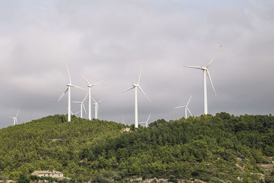 Windmills in field against cloudy sky