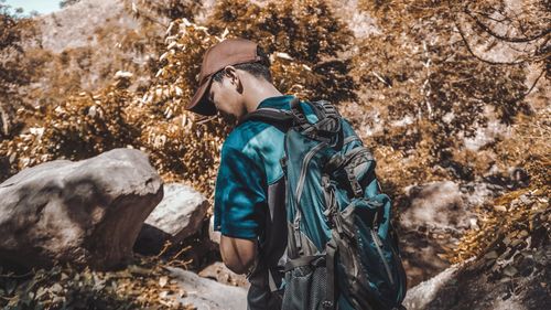 Side view of young man standing against trees during winter