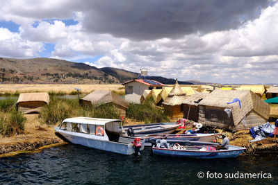 Boats moored on river by buildings against sky