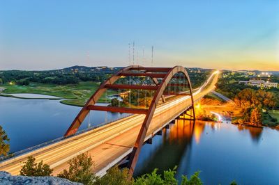 Bridge over river in city against clear blue sky