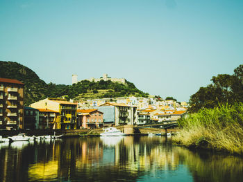 River amidst buildings in town against clear sky