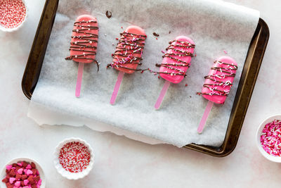 Homemade cakesicles drizzled with candy melts and decorated with sprinkles.